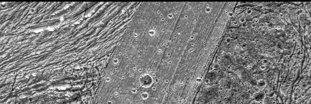 Imagen en blanco y negro de la superficie de Ganímedes, mostrando una mezcla de campos de hielo, cráteres y estructuras geológicas, evidenciando la historia geológica del satélite.